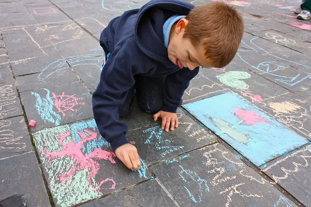 Junge malt mit Straßenkreide