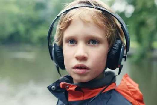 Autismus und Wahrnehmung: Autistisches Kind mit geräuschdämmenden Kopfhörern
