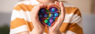 Kinderhände um ein herzförmiges Fidget-Toy