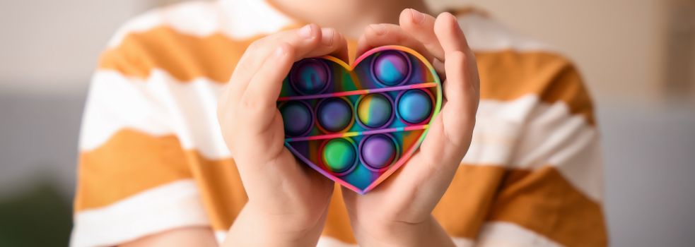 Kinderhände um ein herzförmiges Fidget-Toy