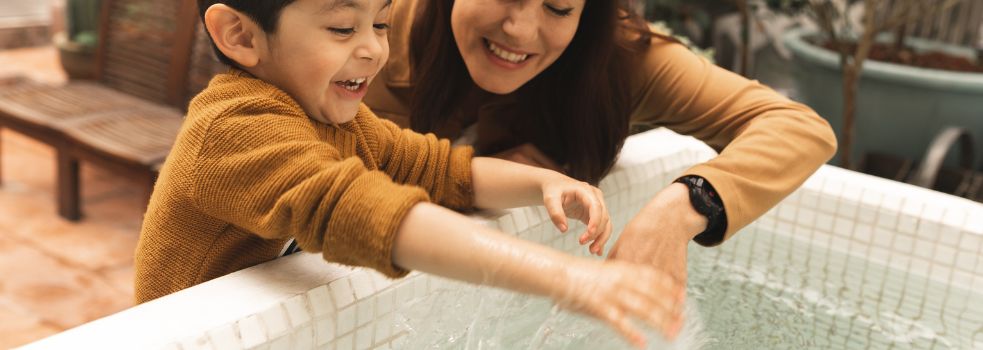 Mutter und Kind spielen mit Wasser